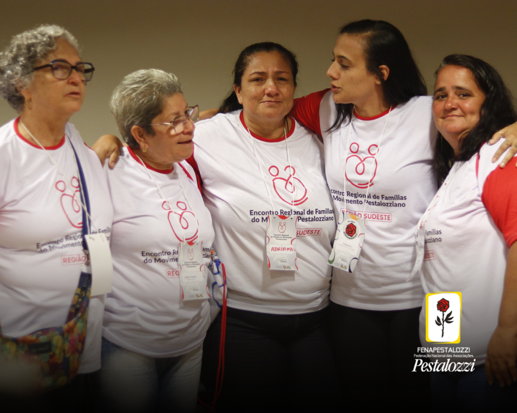 Fotomontagem. No canto inferior direito há a marca completa da Federação Nacional das Associações Pestalozzi com o ícone do Movimento Pestalozziano: um botão de roseira na cor vermelha, caule, folhas e contornos na cor preta. Este está envolvido em uma moldura amarela com fundo branco. Ao centro, foto em plano geral de um grupo de mulheres que participam do Encontro de Famílias. Elas vestem uma camiseta branca de mangas vermelhas e os seguintes escritos: Encontro Regional de Famílias. Região Sudeste. Elas estão enfileiradas, abraçadas lateralmente e se mostram emocionadas. 