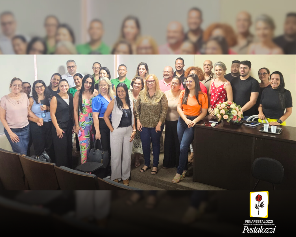 Fotomontagem com a parte inferior ligeiramente escura e com a marca da Fenapestalozzi no canto inferior direito. Trata-se de um desenho de botão de roseira na cor vermelha com contornos, caule e espinhos na cor preta. Este está envolvido em uma moldura amarela com fundo branco. Ao centro, sobrepostas duas fotos, uma desfocada e outra nítida. Trata-se do retrato em plano geral dos participantes da reunião. Ester Pacheco, presidente da Fenapestalozzi está ao centro. Ela veste uma camisa com marca de animais e uma calça jeans azul. Ela é uma mulher branca de cabelos loiros na altura dos ombros, e está usando óculos de grau com armação na cor vermelha.